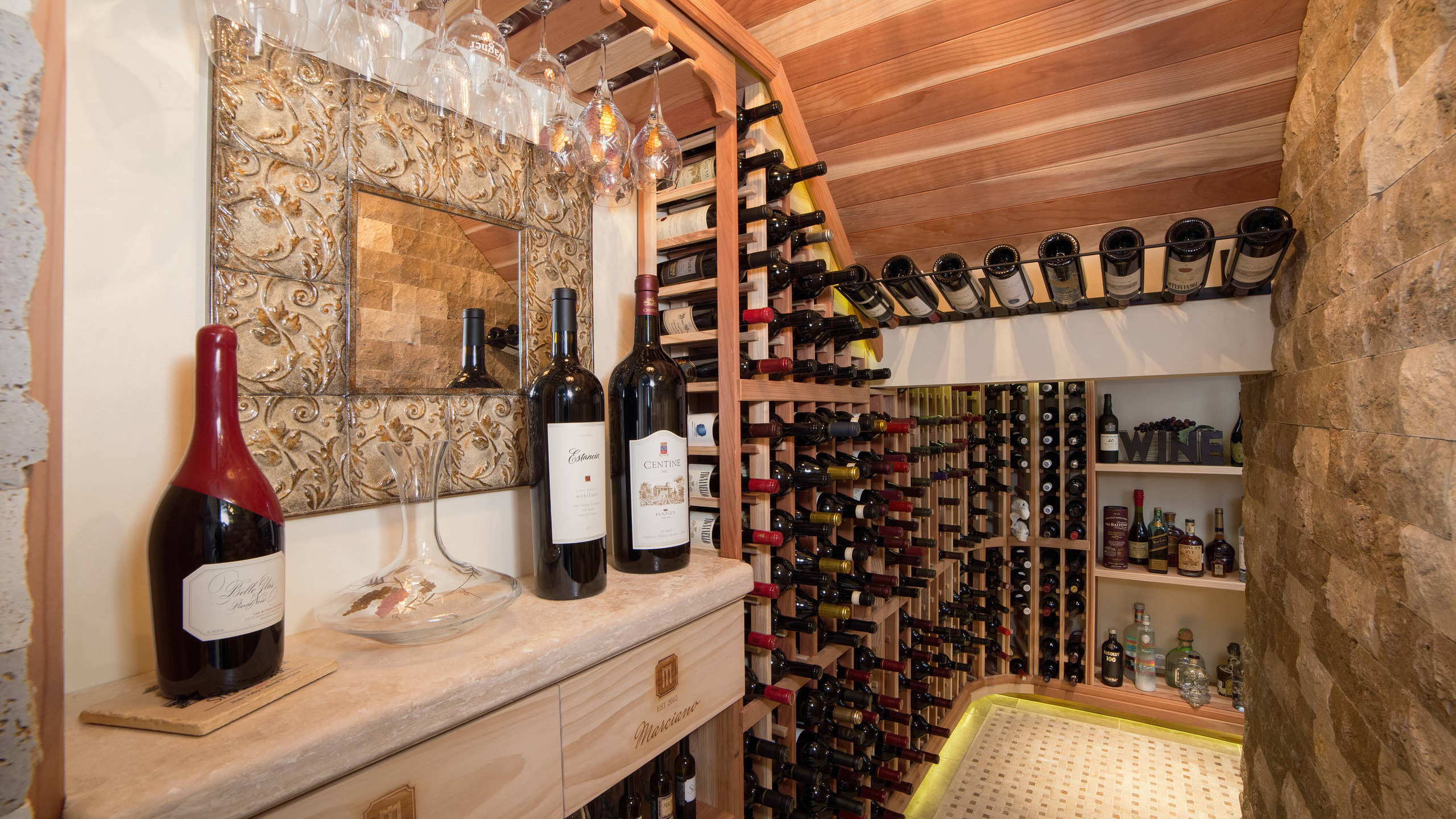 Custom wine cellar with wood wine racks, stone finishes, and wine storage in a Phoenix home remodeled by Hochuli Design & Remodeling Team.