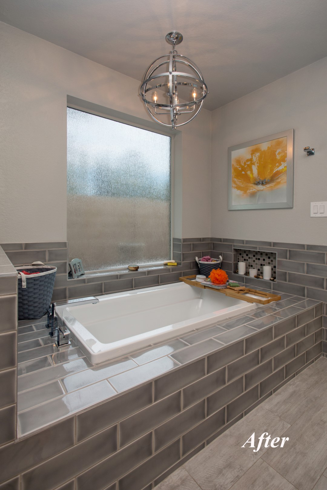 New tub area at the Tempe bathroom remodel with a drop-in bathtub in a Grace Grigio brickset tile surround, chrome metal globe chandelier overhead, and rain-glass privacy window.
