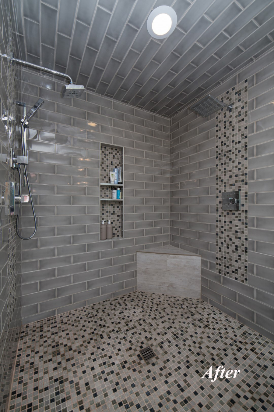 Inside the new walk-in shower at the Tempe bathroom remodel with two showerheads, recessed niche, vertical mosaic accent band, tile bench, and mosaic tile floor.