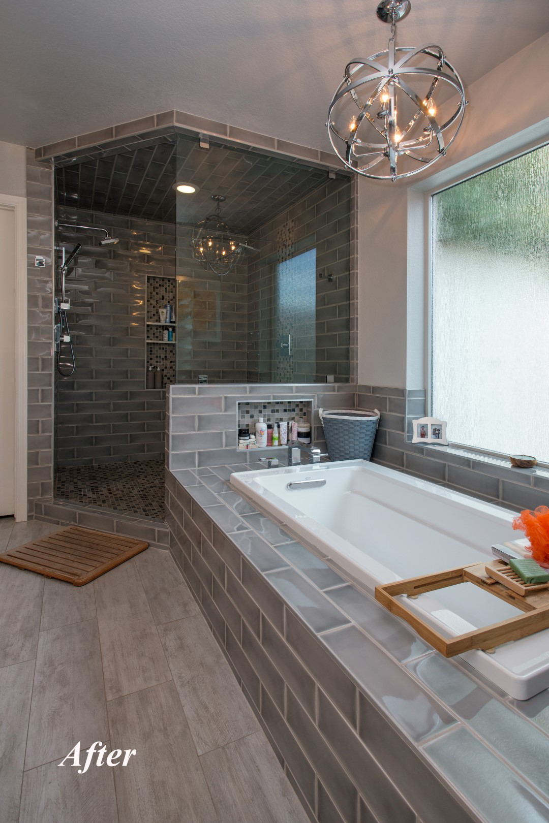 Wide view of the Tempe bathroom remodel showing the new walk-in shower with chandelier inside, the drop-in tub under a chrome metal globe chandelier, and the rain-glass privacy window.