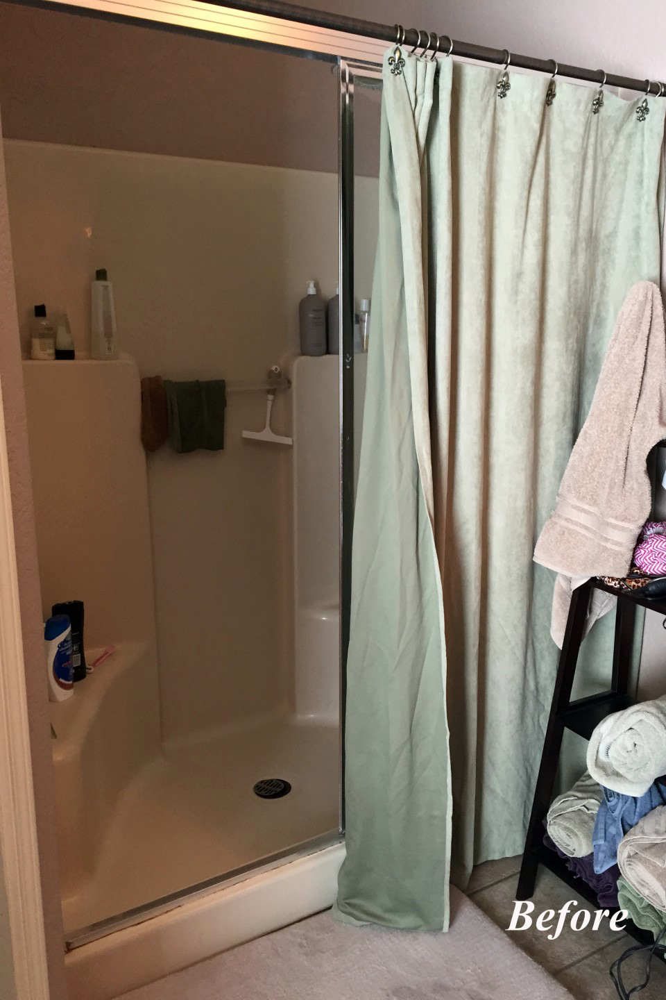 Original shower at the Tempe bathroom with a small fiberglass insert, water-stained glass door, and a fabric curtain hung over the door to hide the staining.