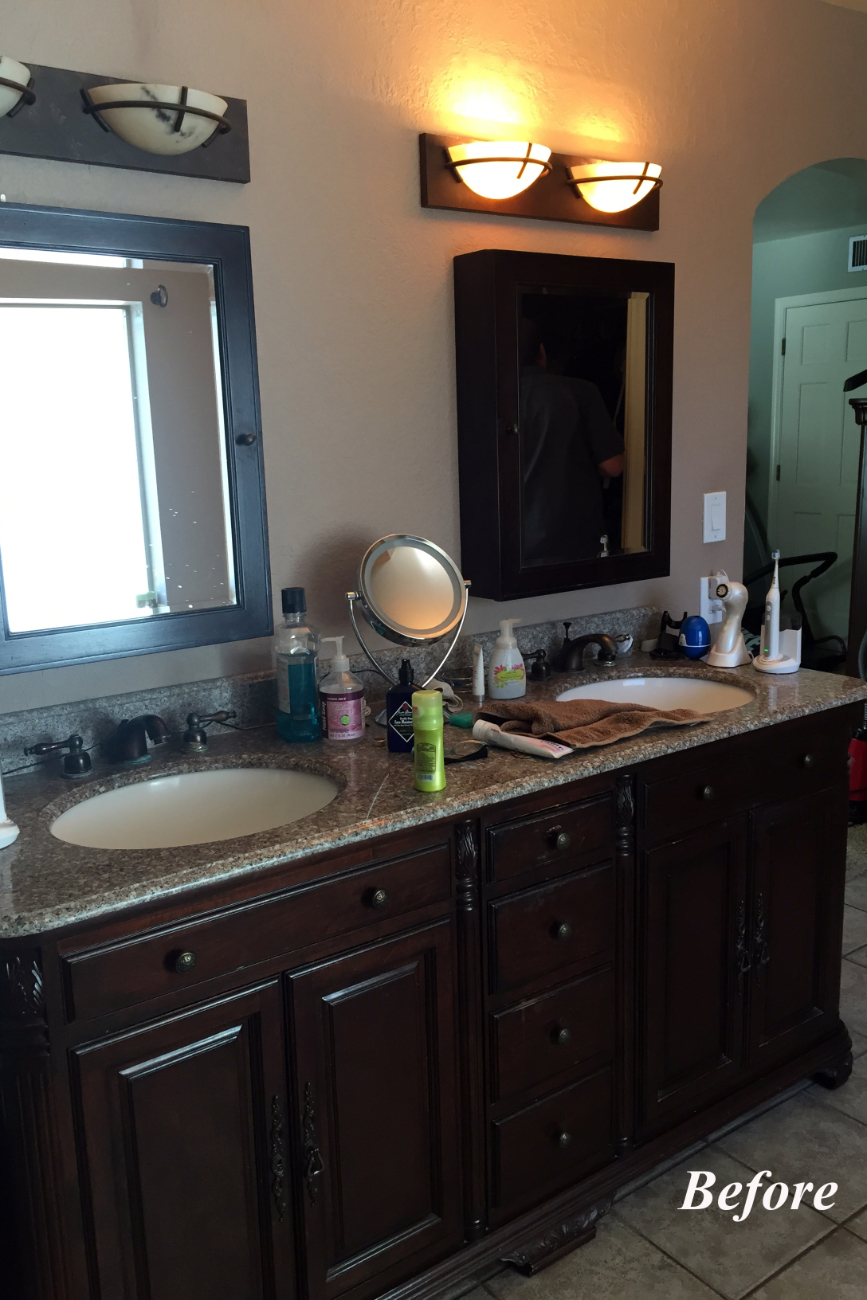 Original vanity in the Tempe bathroom with dark wood cabinets, brown granite countertops, dated lighting, and a wall-mounted dark-stained medicine cabinet.