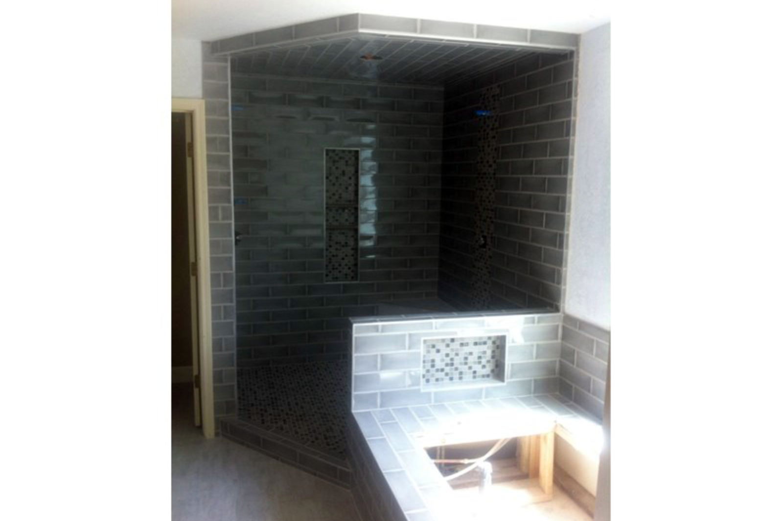 Tile work in progress at the Tempe bathroom remodel with Grace Grigio brickset wall and ceiling tile, Kismet Fate mosaic accent in the shower niche and vertical band, and matching mosaic in the tub niche across the room.
