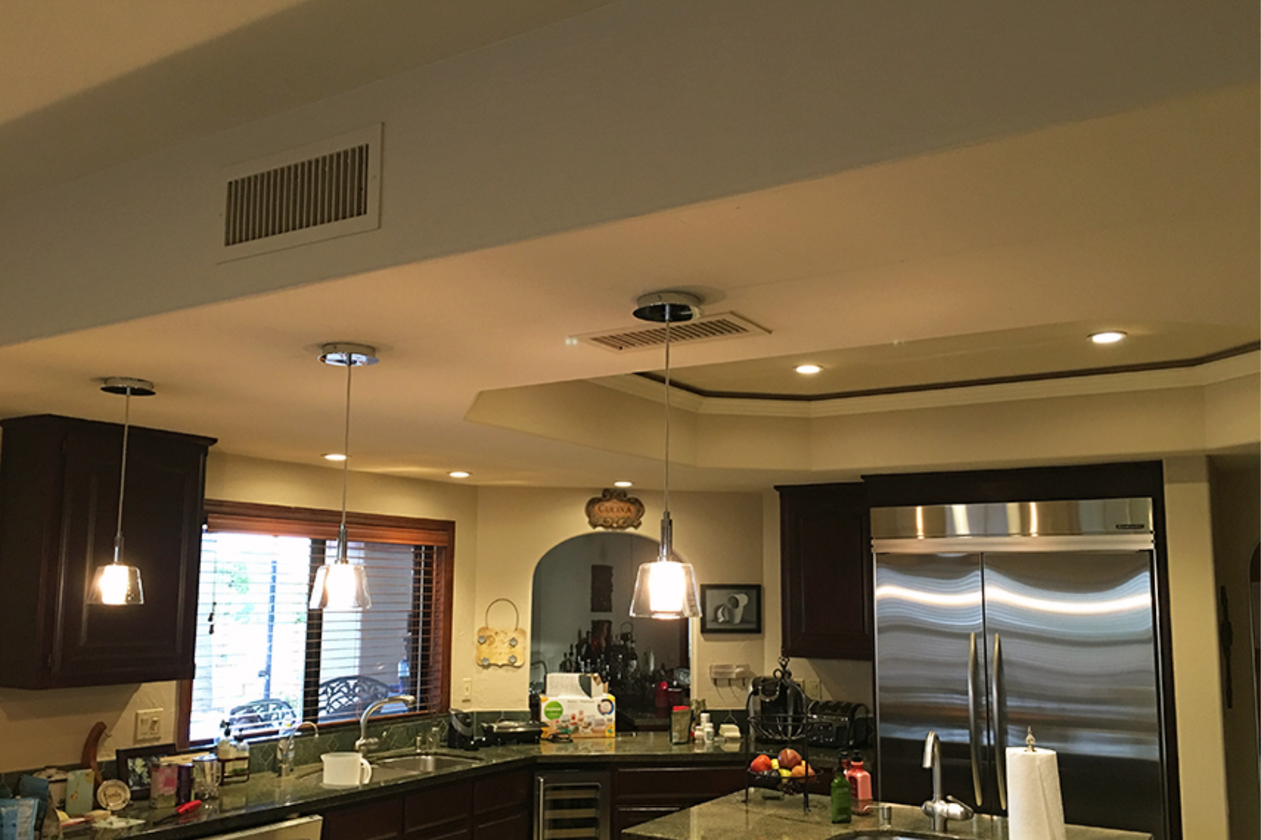 Original ceiling in the Phoenix kitchen with dropped soffit, HVAC vents, and recessed can lights, with dark cabinets visible below.
