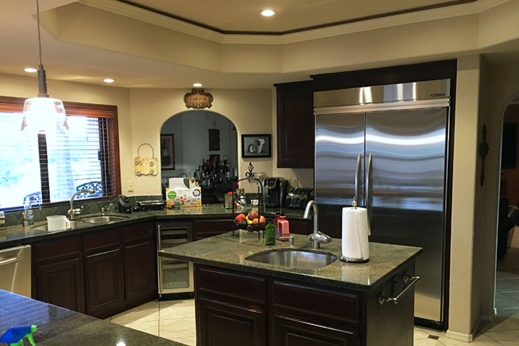 Original Phoenix kitchen layout with dark cabinets, peninsula counter, dropped ceiling, and large stainless refrigerator.