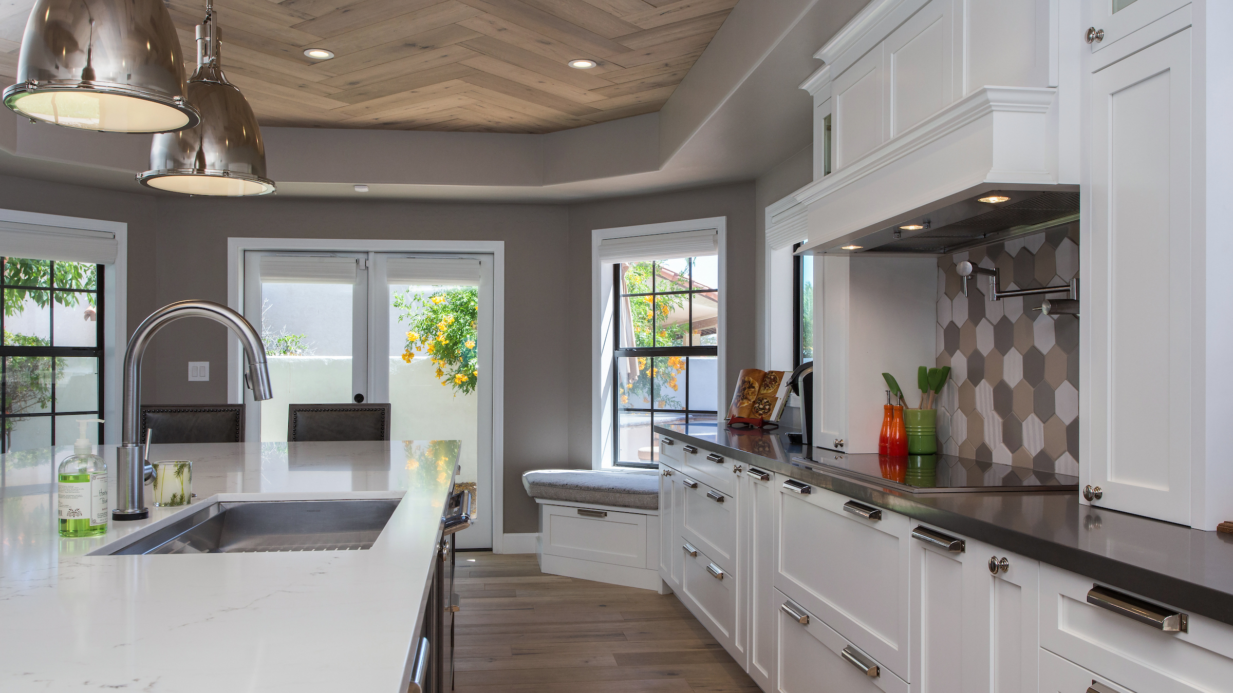 Wood-plank ceiling kitchen in Phoenix showing herringbone French White Oak ceiling, white perimeter cabinets with chrome hardware, quartz countertops, hexagonal Walker Zanger KNIT tile backsplash, and matching French White Oak floor in a single frame.